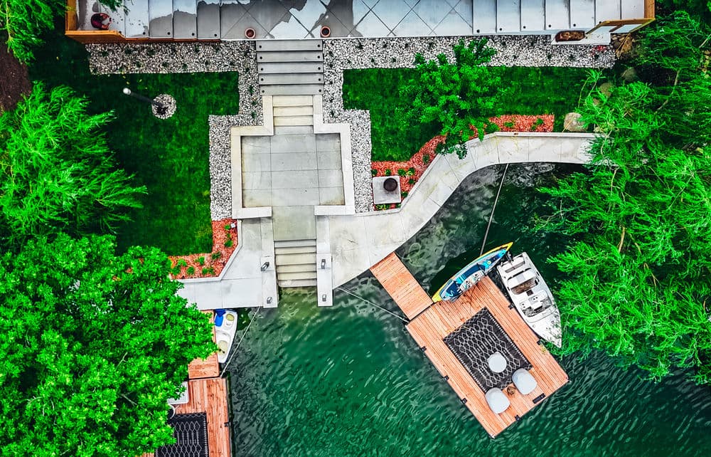 Aerial view of a waterfront property with modern steps, docks, and lush greenery.