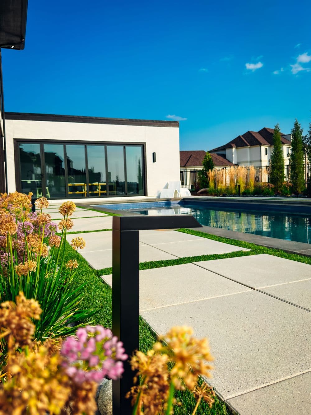 Modern home with a swimming pool and landscaped garden featuring vibrant flowers.