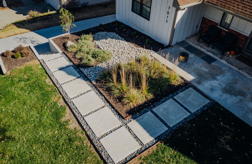 Modern landscape design featuring stone pathways, gravel beds, and decorative plants.
