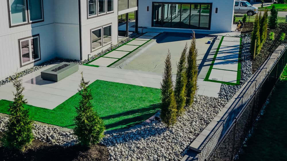 Modern backyard with landscaped artificial grass, patio, and a covered pool area.