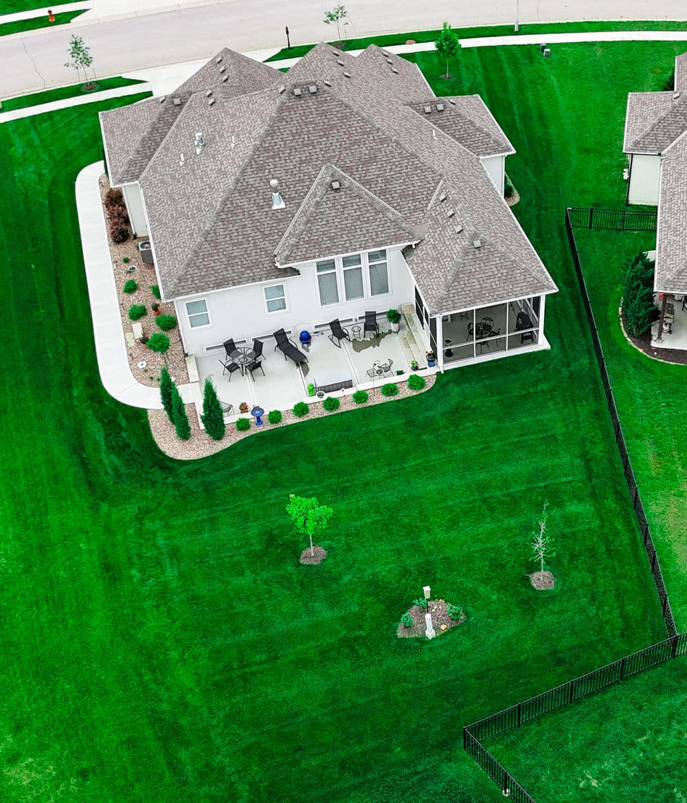 Aerial view of a modern home with a lush green lawn and landscaped backyard.