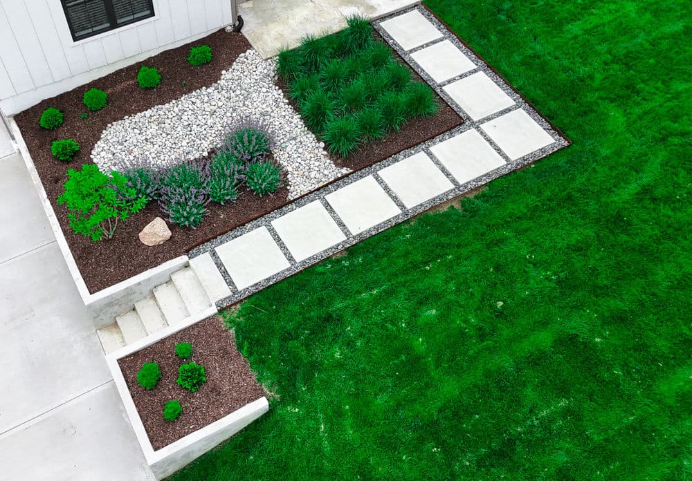Lush green lawn with modern stone pathway and decorative gravel landscaping design.