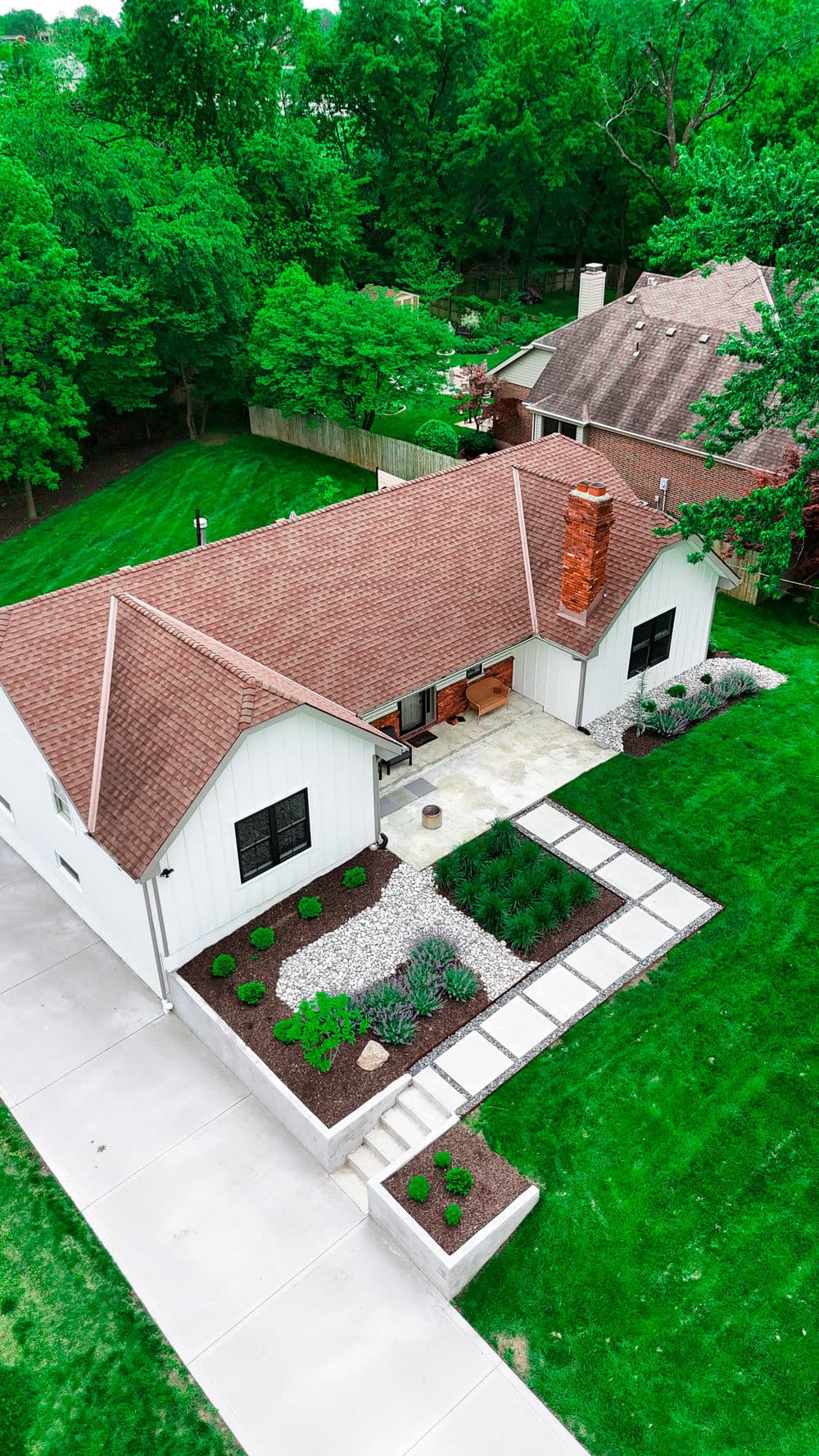 Aerial view of a modern white house with landscaped yard and stone pathway.