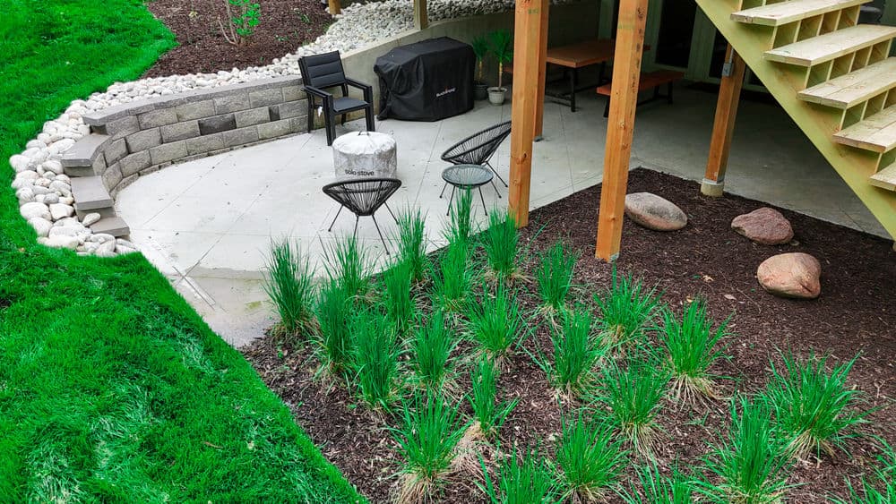 Outdoor patio with gravel seating area, modern chairs, and landscaped greenery.